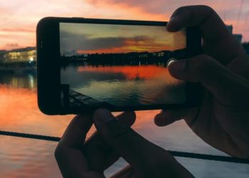 cropped-man-hands-taking-picture-with-mobile-phone-sunset.jpg