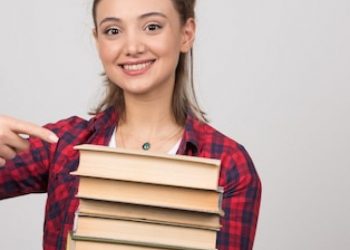 smiling-woman-pointing-stack-books_114579-70564
