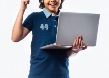Asian,Indian,School,Kid,Holding,And,Using,Laptop,While,Standing